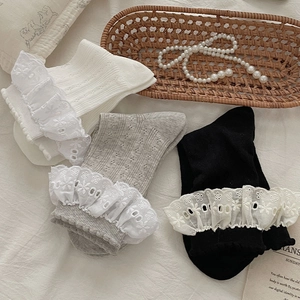 Dettaglio calzini in maglia con pizzo bianco, grigio e nero e ricami floreali eleganti