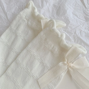 Detail of white mesh knit socks featuring silk bows and elegant lace ruffle trim