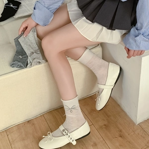Detail of ribbon bow and silver heart pendant on ribbed mid-calf socks for women