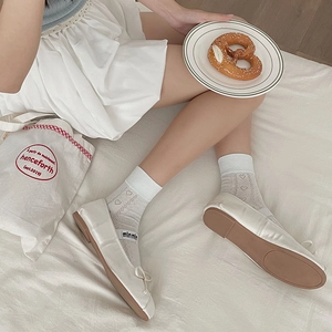 Detail of white heart mesh socks paired with satin ballet flats and delicate bow accents