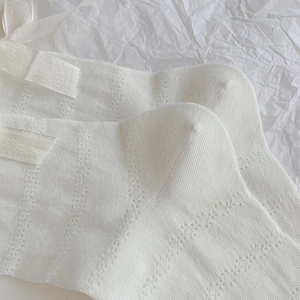 Close-up of white mesh knit crew socks featuring sweet ribbon bow and breathable dot pattern
