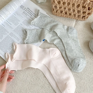 Dettaglio della maglia dei calzini con bordo a volant in grigio chiaro e rosa tenue