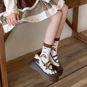 Close-up of white crew socks with cherry heart patterns and brown Mary Jane shoes