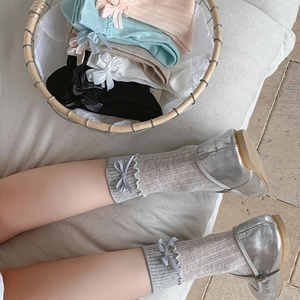 Detail of ruffle cuff and ribbon bow on ribbed knit socks in various pastel colors