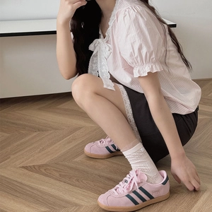 Détail de chaussettes blanches en dentelle fleurie portées avec des baskets roses en daim