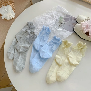 Close-up of hollowed-out mesh socks with sweet bow knots in grey, blue, and yellow