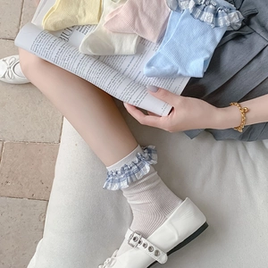 Detail of ruffled lace cuffs on pastel colored mid-calf socks with floral plaid patterns