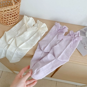 Close-up of mesh knit socks with sweet ribbon bows in white and soft lavender
