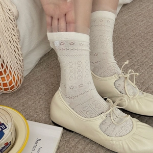 Détail de la dentelle et du bouton blanc sur des chaussettes ajourées blanc crème
