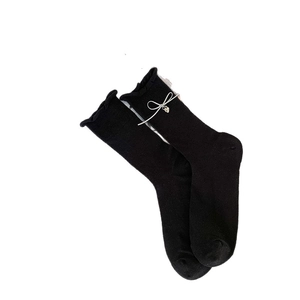 Black crew socks with ruffled cuffs featuring a white bow and silver heart pendant