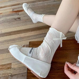 Cream Mary Jane shoes with white bow ribbon lace socks on a wooden stool