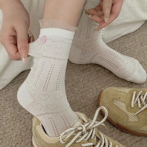 Détail de chaussettes en dentelle blanche avec boutons floraux 3D et motifs cœurs