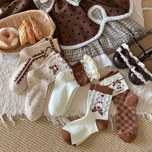 Detailed close-up of sweet lace socks with cherry patterns and bow ties in brown tones