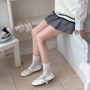 Scarpe Mary Jane bianche con fiocco e fibbia indossate con calze a rete da donna