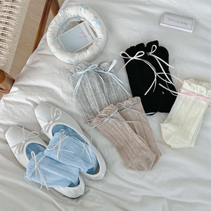 Detail of sheer lattice knit socks with delicate ribbon bows in various pastel colors