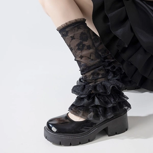 Close-up of black lace leg warmers with floral embroidery and ruffled gothic hems