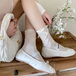 Detailed texture of white lace mesh socks with ribbon bows in a vintage aesthetic