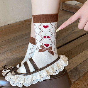 Detail of sweet lace socks with cherry patterns and bow, styled with brown Mary Janes