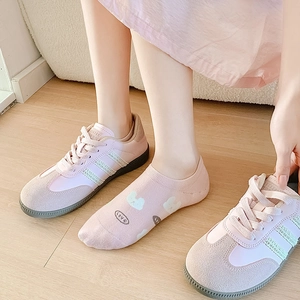 Close-up of pink suede sneakers with matching rabbit pattern socks on a wooden floor