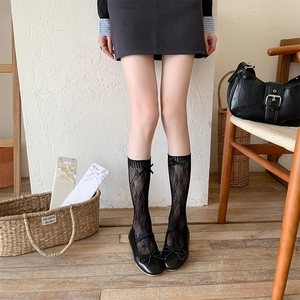 Close-up of lace mid-calf socks featuring diamond patterns and black bow decorations