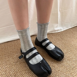 Close-up of Tabi toe Mary Janes with matte black leather and double buckle straps