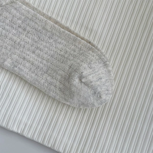 Détail d'une chaussette gris clair montrant la maille fine et la texture côtelée