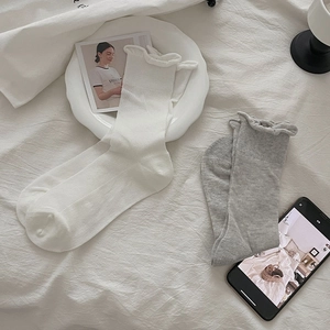 Close-up of ribbed cotton socks with ruffle cuffs in white and grey colors