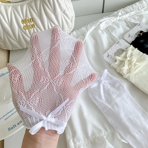 Detail of white mesh lace socks with bow accent and breathable floral pattern texture