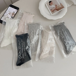 Close-up of five pairs of pastel cotton socks with wavy edges in individual zipper bags