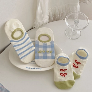 Detail of striped and checkered low-cut cotton socks set on a minimalist white plate