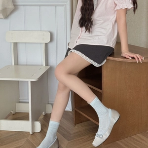 Gros plan de chaussettes en dentelle bleu clair ajourée et chaussures Mary Jane argentées