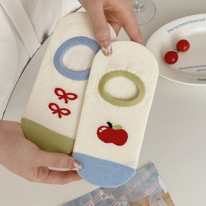 Detail of striped cotton socks with red bow and apple embroidery on off-white fabric
