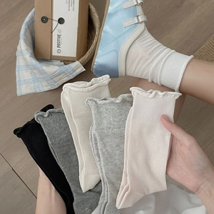 Detail of sheer ribbed socks with ruffled edges in black, grey, cream, and pink colors