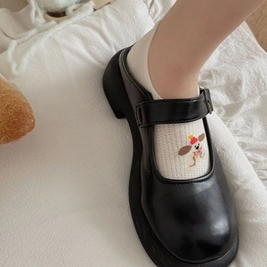 Detail of black platform Mary Jane shoes with metal buckle on white fabric background