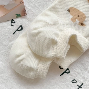 Detail view of cream-white knitted ankle socks featuring cute brown bear embroidery