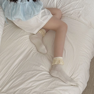 Japanese ballet style beige crew socks with lace trim and vertical stripes on bed