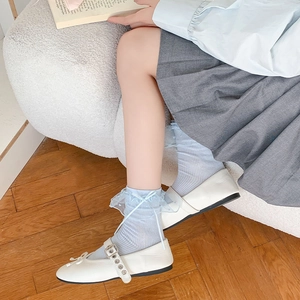 Dettaglio di calzini in pizzo azzurro con fiocco e scarpe Mary Jane bianche