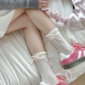 Detail of white cotton socks with pink ribbon bows and subtle argyle knit pattern