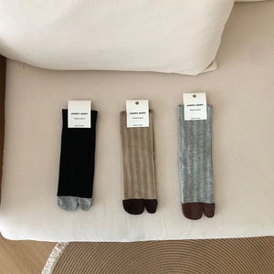 Flat lay of ribbed tabi socks with contrast toe detail on a neutral fabric background