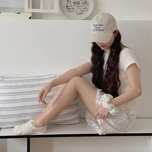 Lifestyle view of white polka dot low cut socks paired with a floral skirt and casual outfit