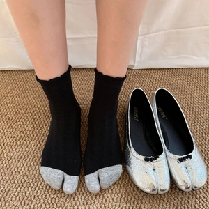 Close-up of Tabi socks with split-toe design and metallic silver ballet flats with buckles