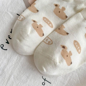 Close-up of a white cotton boat sock featuring a cute brown puppy motif and cute text