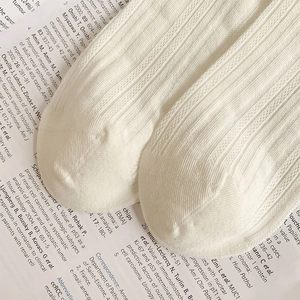 Macro shot of white ribbed knit cotton socks showing detailed texture on newspaper