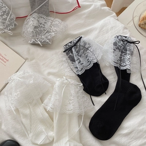 Détails des chaussettes en dentelle avec rubans et nœuds sur un fond en tissu doux