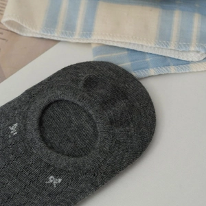 Detailed close-up of dark grey low-cut boat socks with white bow pattern and ribbed cuffs