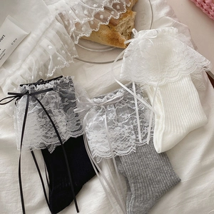 Détail de trois paires de chaussettes à bordure en dentelle et nœuds noirs, gris et blancs