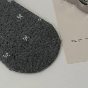 Close-up of grey boat socks featuring white bow jacquard and ribbed knit texture