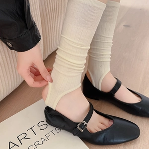 Detailed texture of off-white ribbed leg warmers paired with black Mary Jane shoes