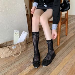 Detail of lace hollow-out mesh socks with silk bows on wood floor background