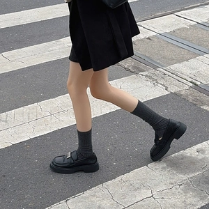 Urban style shot of black platform loafers with silver buckle and grey ribbed socks